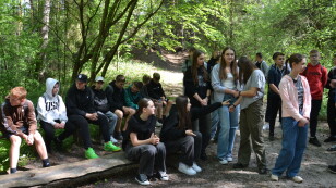 Uczniowie słuchają przewodnika w roztoczańskim lesie.