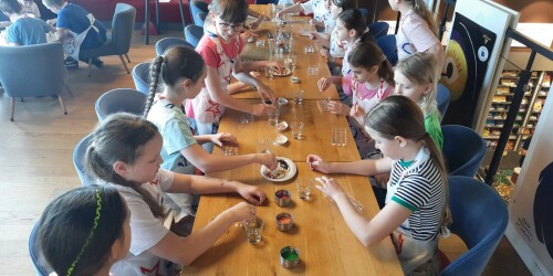 Uczniowie wybierają ulubione składniki do czekolady  i układają je w specjalnej foremce.