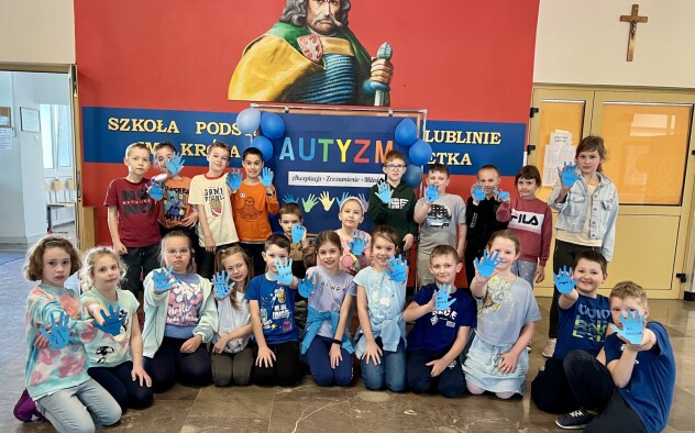 1.Dzień Świadomości Autyzmu. Klasa 2a z niebieskimi łapkami, obok napisu AUTYZM przed patronem szkoły.
