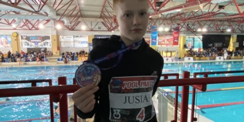 Brązowy medalista z medalem na tle basenu w Dębicy.