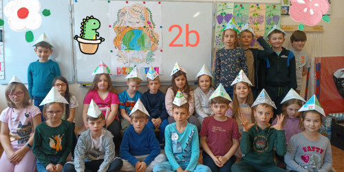 Uczniowie klasy 2 b pozują do zdjęcia w ozdobnych czapkach wykonanych z papieru.