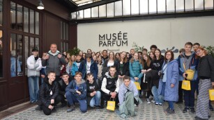 Dziewczynki i chłopcy wraz z opiekunami wycieczki stoją na tle wejścia do Muzeum Perfum Fragonard.